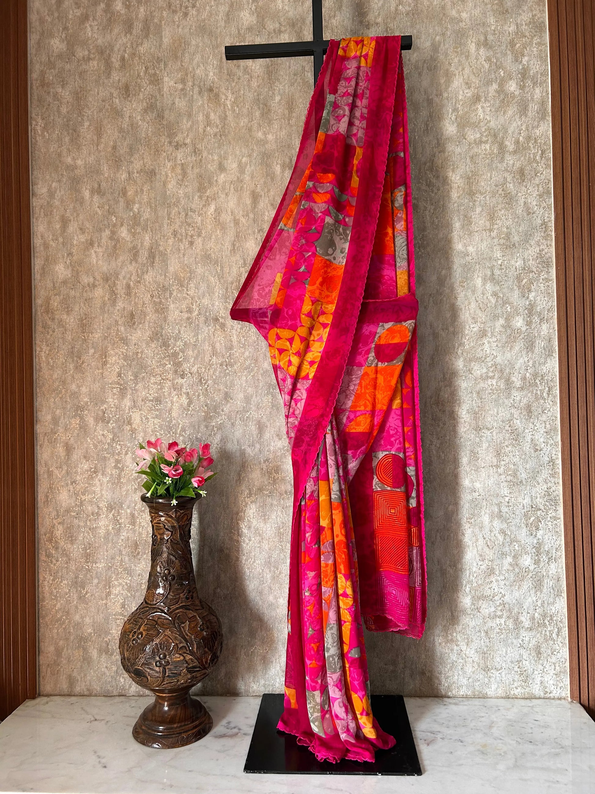 Colorful fabric on a stand with a decorative vase and flowers on a textured surface