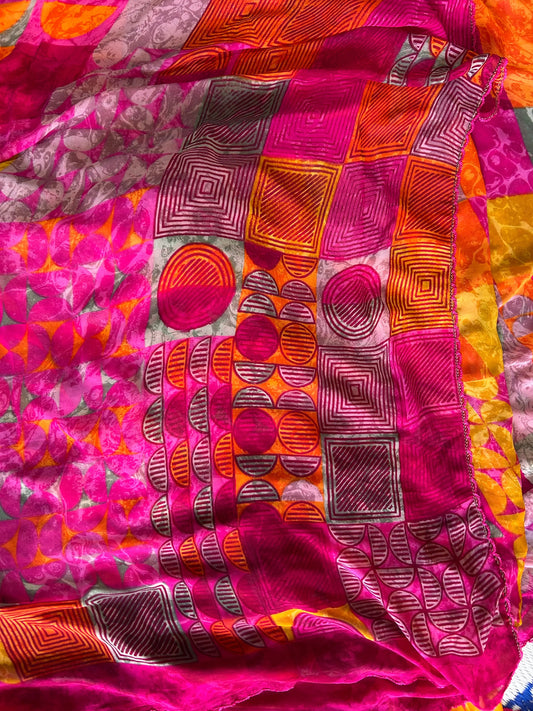 Close-up of a colorful fabric with geometric patterns in pink, orange, and purple.